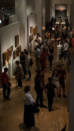 a group of people standing around in a room with pictures on the wall behind them