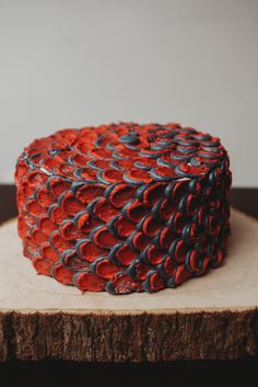 a red and blue cake sitting on top of a wooden slice