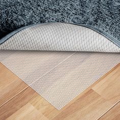 a close up of a rug on the floor next to a wooden floor with a gray and white area rug