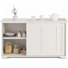 a white cabinet filled with dishes and cups on top of it's shelf next to a vase