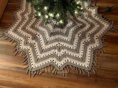 a crocheted afghan under a christmas tree on the floor with lights in it