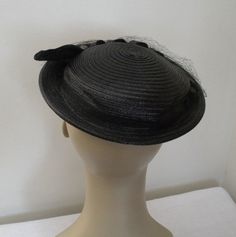 "This is a black straw hat with a small brim. It has a looped straw and velour accent along the front ends in a flat \"feather\" piece. There are clear bugle beds to start and then the piece of straw flattens and is edged in velour and dotted with rhinestones. There is a black veil but from the little bit that I could pull down it seems to have quite a few holes and seems to be caught in places that does not allow it to come down over the face. The hat is in very nice 1940's - 1950's vintage con Black Adjustable Boater Hat For Formal Occasions, Black Short Brim Boater Hat For Church, Adjustable Fedora Mini Hat For Church, Black Hat Bands For Evening With Short Brim, Black Mini Hat With Short Brim For Church, Adjustable Black Mini Hat For Church, Black Straw Hat With Curved Brim For Evening, Black Straw Hat With Flat Brim For Party, Black Straw Hat With Short Brim For Party