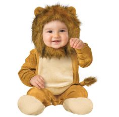 a baby in a lion costume sitting on the ground with his hand up to his face