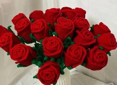 a white vase filled with red roses on top of a table