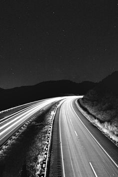 an image of a highway at night with light streaks on the road and stars in the sky