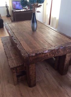 a wooden table sitting in the middle of a living room with a vase on top of it