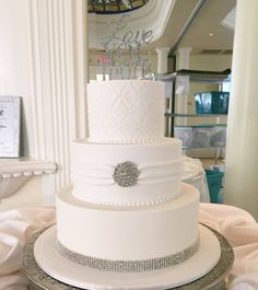 a three tiered white wedding cake sitting on top of a table