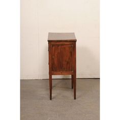 an old wooden cabinet sitting on top of a cement floor next to a white wall