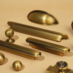 several brass handles and knobs on a beige surface