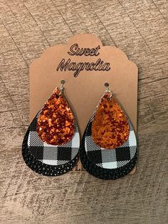 the black and white checkered tear shaped earrings are adorned with orange glitter