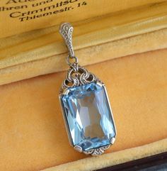 "Vintage 1930s blue topaz 935 silver pendant. Beautiful and quality German Art Deco jewelry piece! Height incl. loop 3.5 cm (1.4\"), width 1.3 cm (0.5\"), the stone 16 mm x 11 mm Weight: 4.7 grams Hallmarked: 935 for high grade silver  Excellent vintage condition The box on the photos for display only! Will be delivered by tracked and signed mail. Thank you for looking. Please see my other items." Elegant Hallmarked Rectangular Pendant Jewelry, Art Deco Sapphire Jewelry With 17 Jewels, Sapphire Art Deco Jewelry With 17 Jewels, Antique White Gold Jewelry With Large Pendant, Formal Aquamarine Pendant Jewelry, Art Deco Pendant Jewelry For Anniversary, Elegant Light Blue Drop Jewelry, Classic Light Blue Jewelry For Formal Occasions, Classic Light Blue Formal Jewelry