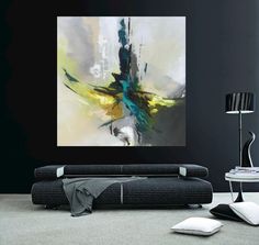 an abstract painting on the wall above a black couch in a living room with white pillows