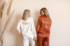 two women standing next to each other wearing matching pajamas and sweatshirts with the word bride printed on them