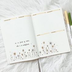 an open notebook with writing on it and two pens laying next to each other in front of a white furry surface