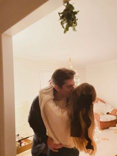 a man and woman are kissing in the living room with christmas lights on the ceiling