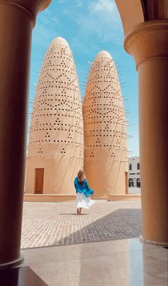 a woman is standing in front of two large domes with holes on the roof and walls