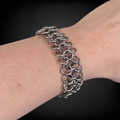 a woman's arm with a silver chain bracelet on it, and the clasp is open