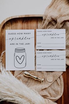 the wedding stationery is laid out on top of a wooden tray with a pen and paper