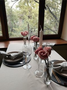 a table set with place settings and flowers in vases on top of the table