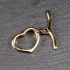 Size: Eyelet (heart): 17.5 x 4.7 x 2.2 mm Rod: 25.1 x 1.7 mm Thread eyelet: 3 mm Material: brass, 24 carat gold plated Quantity: 1 set Item number: 11096 This toggle clasp in a minimalist heart design is ideal for bracelets and necklaces. The clasp is made of high-quality brass and is 24-carat gold-plated, giving it a luxurious look. The heart loop measures 17.5 x 4.7 x 2.2 mm, the bar has a length of 25.1 x 1.7 mm, and the threading loop has a diameter of 3 mm. The toggle clasp is not only func Heart-shaped Jewelry With Clasp For Gifts, Heart-shaped Jewelry Gift With Clasp, Gold Toggle Necklace For Valentine's Day, Valentine's Day Gold Toggle Necklace, Gold Heart Toggle Necklace With Toggle Clasp, Gold Heart-shaped Toggle Necklace, Gold Metal Toggle Necklace With Heart Charm, Gold Heart Toggle Necklace With Lobster Clasp, Heart Shaped Jewelry With Toggle Clasp For Anniversary