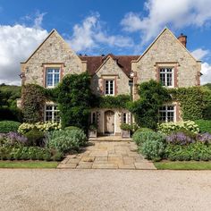 a large stone house surrounded by greenery and flowers