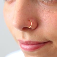 a close up of a person with a nose ring on their nose, wearing a white shirt