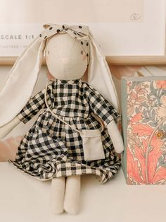 a stuffed rabbit sitting next to a book on a table with an old fashioned greeting card