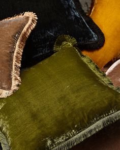 three velvet pillows with fringe trims on top of each one in various colors and sizes