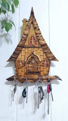 a wooden cuckoo clock with keys hanging from it's side on a white wall