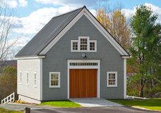 a gray and white house with a red garage door on the front yard, surrounded by trees