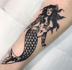 a black and white tattoo design of a mermaid on the arm with fish tailes