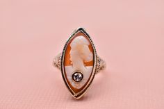 Vintage Art Deco 14K white gold filagree carved shell cameo and diamond ring. The ring is in excellent condition with little visible wear. The ring is set with one marquise carved shell cameo measuring approximately 19mm long by 9mm wide featuring a light orange color. It is also set with one bezel set single cut round diamond weighing approximately 0.08cts featuring a color of H-I and a clarity of VS1. The ring weighs 2.40 grams and is a finger size 4.5. The shank measures 3.29mm at the shoulders and 1.59mm at the bottom. The max width at the top of the ring is 21.73mm. Appraisal Value: $1200. This ring will be shipped in a vintage suede hand made ring box. These can be purchased separately from my store as well in an array of colors. This information is all 100% accurate and being sold b Gold Art Deco, Carved Shell, Vintage Suede, Gold Art, Light Orange, Vintage Art Deco, Bezel Setting, Rings Statement, Round Diamond