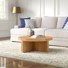 a living room with white couches and blue pillows on the sofa table, along with a coffee table