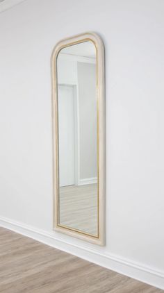 an empty room with a mirror on the wall and wood flooring in front of it