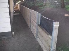 a wooden fence with a black tarp over it and some dirt on the ground