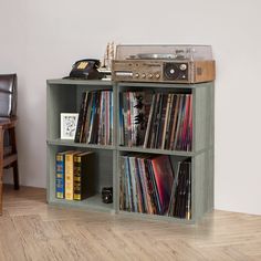 a record player is sitting on top of a book shelf filled with cds and records