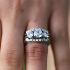 a woman's hand with two diamond rings on top of her wedding band,