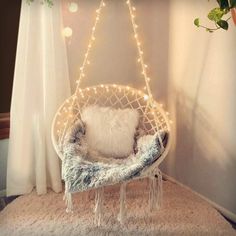 a hanging chair with lights on it in a room next to a potted plant