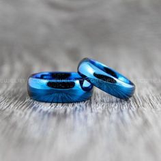 two blue wedding rings sitting on top of a wooden table