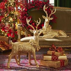 two gold deer figurines sitting next to christmas presents in front of a couch