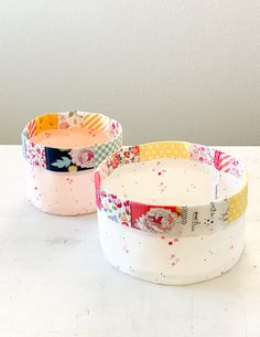 two bowls with different designs on them sitting next to each other in front of a white wall