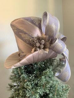 a hat is sitting on top of a christmas tree with ribbons and pineconis