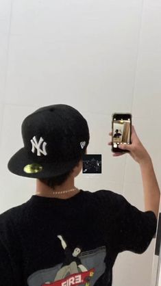 a person wearing a hat taking a selfie with a cell phone in their hand