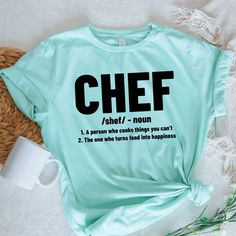 a t - shirt with the words chef on it next to a cup and wicker basket