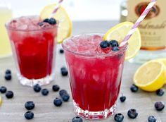 two glasses filled with blueberries and lemonade on top of napkins next to each other