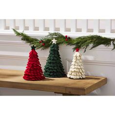 three small christmas trees sitting on top of a wooden table