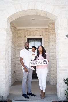 a man and woman standing in front of a door holding a sign that says address us