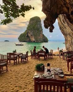 an outdoor dining area on the beach with people sitting at tables and looking out to sea