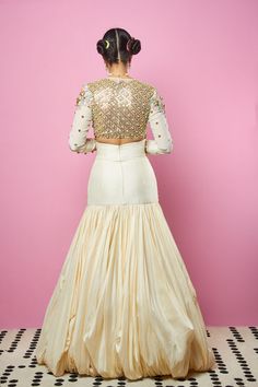 An ivory V-neck embellished full sleeves blouse with 3D embellished shoulder detail, front, back, and sleeve embellished using, metallic motifs, glass beads, gold reflective acrylics, pearls, and sequins.An ivory Dupion silk lehenga hand draped with a 3D embellished yoke using glass beads, metallic fittings, stones, gold reflective acrylics and neon sequins.From Papa Don’t Preach’s Zsa Zsa Zsu collection. DELIVERY TIMEPlease allow 8-12 weeks for your outfit to arrive. FABRIC DETAILSCrepe, George Long Sleeve Blouse With Pearl Embroidery For Wedding, Long Sleeve Wedding Blouse With Pearl Embroidery, Party Wear Embellished Long Sleeve Sharara, Party Wear Long Sleeve Embellished Sharara, Glamorous Festive Lehenga With Pearl Embroidery, Embellished Long Sleeve Sharara For Party Wear, Long Sleeve Embellished Sharara For Party Wear, Glamorous White Hand Embellished Sets, Designer Raw Silk Lehenga With Pearl Embroidery