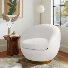 a white chair sitting on top of a wooden floor next to a table and window